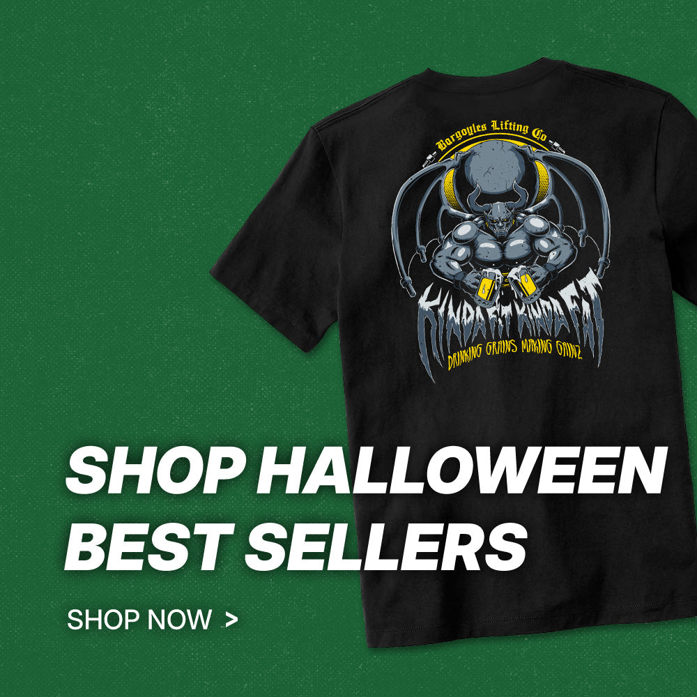 A black short-sleeve graphic T-shirt shown on a dark green promotional background with large white text reading 'SHOP HALLOWEEN BEST SELLERS' and 'SHOP NOW >'. The shirt features a large back graphic of a skull and muscular arm with the words 'Beware the Lifting of Us' and 'SHADERS WITCHING WITCHING'.