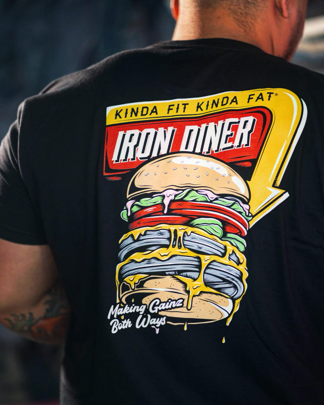 Millennial man wearing Iron Diner T-shirt in black. 