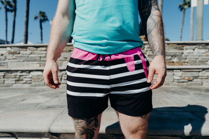 Model wearing Kinda Fit Kinda Fit Black Training Shorts. KFKF Pink Icing Drip along the waistband. OG Donut Logo tag over the right leg 