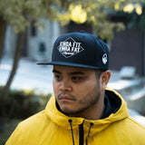 Model wearing Kinda Fit Kinda Fat Diamond Drip Logo Unisex Black Snapback Hat. Front shot.