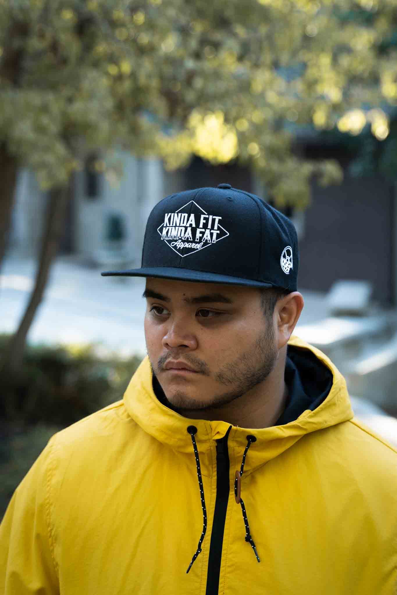Model wearing Kinda Fit Kinda Fat Diamond Drip Logo Unisex Black Snapback Hat. Front shot.